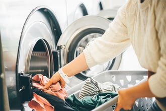 Girl loading dirty clothes inside a commercial washer