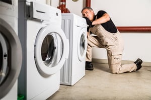 Technician repairing laundry equipment on-site commercial facility