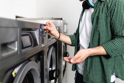 Apartment resident inserting a coin into a vended laundry machine